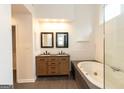 Bright bathroom featuring a double sink vanity with stone countertops, framed mirrors, and a modern white soaking tub at 155 Glenwood Ln, Fayetteville, GA 30215