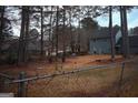 Spacious backyard featuring a lush lawn, mature trees, and a view of the home's back exterior, enclosed by a chain-link fence at 3281 Nina Way, Douglasville, GA 30135