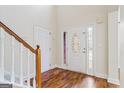 Foyer with wood floors featuring a decorative front door and staircase with white railing at 243 Long Dr, Mcdonough, GA 30253