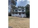 Front view showcasing this two-story home with white siding, a covered porch, and mature trees at 57 Kristina Ct, Acworth, GA 30101