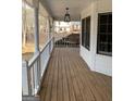 Inviting covered porch featuring wood flooring, hanging lantern, and a charming porch swing at 57 Kristina Ct, Acworth, GA 30101