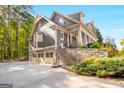 Spacious three-car garage with stone accents and a basketball hoop next to lush greenery at 101 Kenmare Row, Tyrone, GA 30290