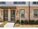 Charming brick townhome featuring covered entry and well-maintained landscaping, creating a welcoming facade at 2624 Caruso Way, Atlanta, GA 30339