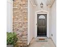 Close up of the house front door with stone accents, a welcome mat and green shrubs at 7764 Parkside Dr, Lithia Springs, GA 30122