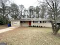 Traditional brick home with a bright red door, surrounded by mature trees and a spacious front yard at 3647 Brookcrest Cir, Decatur, GA 30032