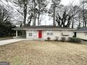 Inviting single-story home featuring a bright red front door, covered carport, and manicured landscaping at 1785 San Gabriel Ave, Decatur, GA 30032