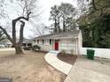 Ranch-style home with a red door, sidewalk, and mature trees in the front yard at 1986 Bandera Dr, Decatur, GA 30032