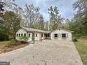 View of the house with a pergola and large concrete driveway surrounded by trees at 1450 Victoria Ln, Oxford, GA 30054
