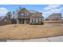 Two-story brick home featuring a covered porch and well-maintained landscaping at 121 Amelia Way, Ellenwood, GA 30294