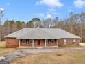 Charming single-story brick home with red front door, a gray roof and a columned front porch at 445 Turner Dr, Mcdonough, GA 30252