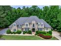 Aerial view of a stunning stone accented home, a pristine lawn and lush landscaping with mature trees at 709 Prestige Pt, Peachtree City, GA 30269