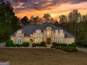 Stunning home at sunset boasts lush landscaping, exterior lighting, and a beautiful mix of stone and siding at 709 Prestige Pt, Peachtree City, GA 30269