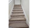 Carpeted staircase featuring white trim and handrail offers a seamless transition between floors in the home at 2764 Keystone Ave, Lithonia, GA 30058