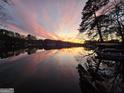 Scenic lake view featuring a vibrant sunset with colorful sky reflecting on the calm water, with trees in the distance at 3140 Jodeco Dr, Jonesboro, GA 30236