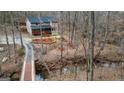 An aerial view of a two-story home, surrounded by mature trees and a small stream and bridge at 613 Rock Springs Pass, Dallas, GA 30157