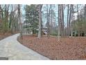 View of the home through the trees along a concrete driveway in a wooded lot at 200 Deer Forest Trl, Fayetteville, GA 30214