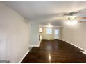 A light-filled living room with dark floors, ceiling fan, and a partial view of the adjacent kitchen at 360 Belgarde Pl, Atlanta, GA 30354