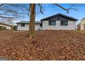 View of backyard with lawn covered in leaves and brick home exterior with dark trim at 6973 Stephens Dr, Rex, GA 30273
