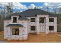 Exterior view of new construction home with dark roof, covered in weather protection at 2015 Fontainbleau Dr, Conyers, GA 30094