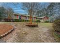 Lovely exterior view featuring a brick facade, red shutters, and a mature tree enhancing curb appeal at 308 Tulipwood Sw Cir, Conyers, GA 30094