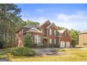 Beautiful two-story red brick home with an attached three-car garage and manicured landscaping at 100 Windmeadow Way, Fayetteville, GA 30214