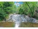 Scenic waterfall flows through a lush forest with sunlight filtering through the trees at 5200A Burruss Mill Rd, Cumming, GA 30041