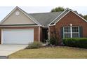 Brick front home featuring a two-car garage, manicured lawn, and well-maintained landscaping around the entrance at 410 Mockingbird Dr, Loganville, GA 30052