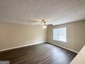 Bright living room with sleek dark floors, a ceiling fan, and a large bright window at 5743 Rock Rd, Union City, GA 30291