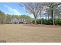A long driveway leads to a beautifully designed house, complemented by a sprawling lawn and mature trees at 115 Foxford Run, Tyrone, GA 30290