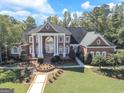 Brick home with manicured lawn and mature trees showcases its symmetrical design and stately white columns at 125 Turnberry Cir, Fayetteville, GA 30215