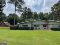 Well-manicured lawn featuring both a red barn and the main home on a sunny day at 225 Banks Rd, Fayetteville, GA 30214