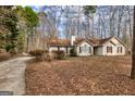 Inviting one-story home with a long driveway, surrounded by a lush, leaf-covered yard and mature trees at 390 Marsha Way, Sharpsburg, GA 30277