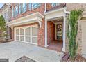Close-up of a brick townhome showcasing the front entry, attached garage and detailed trim and well manicured landscaping at 44 Star Spangled Ln, Peachtree City, GA 30269