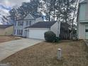 A two-story, gray house with a two-car garage, green lawn, and privacy bushes at 6558 Eastbriar Dr, Lithonia, GA 30058