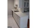 Kitchen with white cabinets, white countertop, stainless steel sink and faucet, and white tiled floor at 4111 Pine Heights Ne Dr, Atlanta, GA 30324