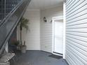 View of a condominium entryway, featuring a white door, small potted tree and plants, and a bench at 4000 Orchard Hill Ter, Stone Mountain, GA 30083