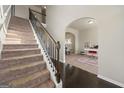Elegant staircase featuring carpeted steps and dark wood railing leading to an upstairs landing at 536 Caledon Way, Hampton, GA 30228