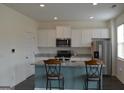 Modern kitchen featuring an island with barstool seating and stainless steel appliances at 1879 Redfern Rd, Dacula, GA 30019