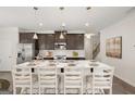 Kitchen island with white countertop, dark cabinets, seating for four, and pendant lighting at 10471 Trellis Lane (Lot 25), Hampton, GA 30228