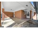 Covered carport featuring brick walls, a concrete floor, and a white door leading into the home at 623 Swan Lake Rd, Stockbridge, GA 30281