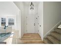 Bright entryway featuring wood floors, a modern light fixture, and access to the living room and staircase at 2391 Wellborn Hills Ct, Lithonia, GA 30058