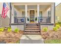 Cozy front porch features dark railing, seating, and elegant potted greenery, framed by classic pillars at 120 Middleton Dr, Peachtree City, GA 30269