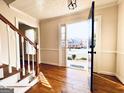 Bright foyer showcasing hardwood floors, a staircase, and an open view to the outdoors through the front door at 5074 Oak Leaf Ter, Stone Mountain, GA 30087