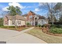 Stunning brick home with a circular driveway and professionally landscaped front yard, creating a grand entrance at 612 Champions Dr, Mcdonough, GA 30253