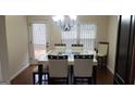 Bright dining room with wood floors, a modern chandelier, and views of the backyard at 7522 Springbox Dr, Fairburn, GA 30213