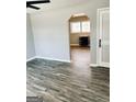 A spacious living room featuring modern gray wood flooring, a doorway, and light gray walls at 23 Hampton Locust Grove Rd, Hampton, GA 30228