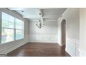 Formal dining room with large windows, decorative chandelier, and classic wainscoting at 207 Birchwood Dr, Loganville, GA 30052