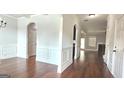 Open-concept living area featuring hardwood floors, wainscoting, and an arched doorway at 207 Birchwood Dr, Loganville, GA 30052