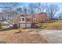 View of split-level house with a two-car garage and a yard with seasonal foliage in a quiet neighborhood at 627 Radford Cir, Woodstock, GA 30188