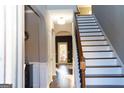 Inviting hallway with hardwood floors and staircase with dark wood trim, leading to a bright entrance at 7625 Bowhead Ct, Fairburn, GA 30213